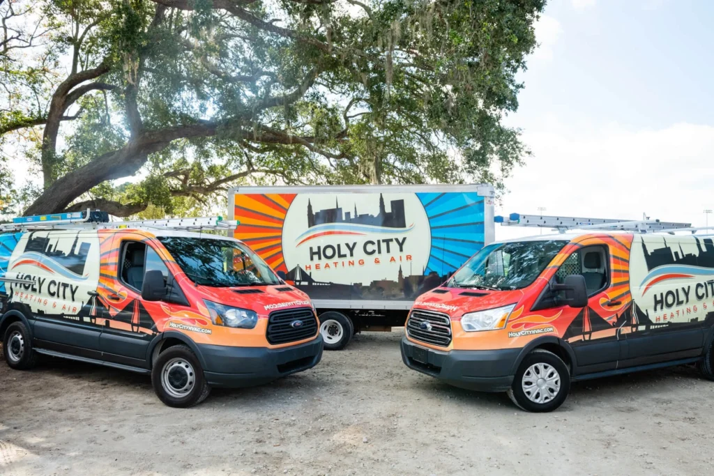 Holy City Heating & Air's wrapped vans and box truck posed under a live oak draped in Spanish moss