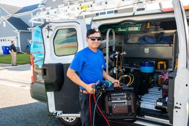 Holy City technician beside a wrapped company van, ready for a service call