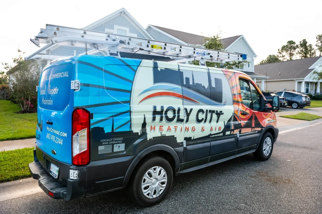 A wrapped Holy City Heating & Air service van parked in a Charleston residential neighborhood